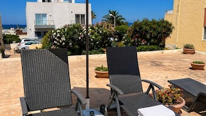 Une terrasse sur le toit, avec deux chaises longues, un parasol et des plantes en pot.