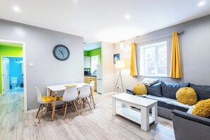 A modern living room with a dining table, sofa, and a view of the kitchen. - Victoria Road by Guestz (Shotton)