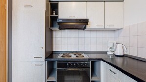 Una cucina compatta con fornello, forno e macchina da caffè.
