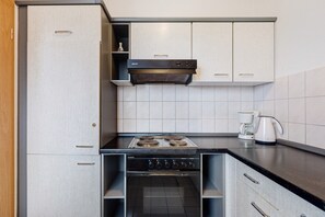 Eine kleine Küche mit Herd, Backofen und Kaffeemaschine.