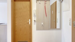Una porta in legno con una maniglia, uno specchio a muro e un interruttore della luce.
