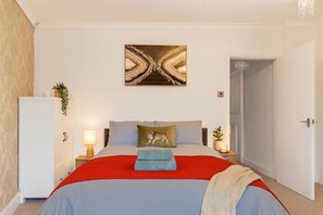 A bedroom with a bed, a nightstand, a lamp, a wall art piece, and a door. - 3 bed Home Workington Near Lake District (Workington)