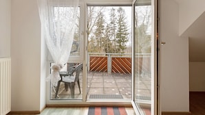 Une pièce dotée d’une porte-fenêtre coulissante donnant sur un espace extérieur agrémenté d’une clôture en bois et d’arbres.