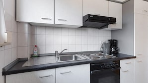 Une cuisine moderne avec des meubles blancs, un évier à deux bacs, une cuisinière et une machine à café.