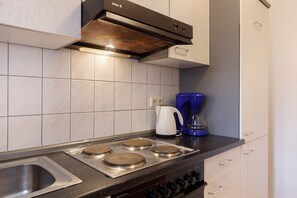 Een keuken met een roestvrijstalen fornuis, een koffiezetapparaat en een blauwe waterdispenser.