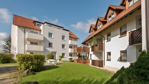 Um edifício residencial com várias varandas, um pátio pavimentado e um gramado bem cuidado.