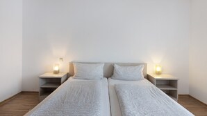 Quarto duplo com duas camas, mesas de cabeceira e abajures.