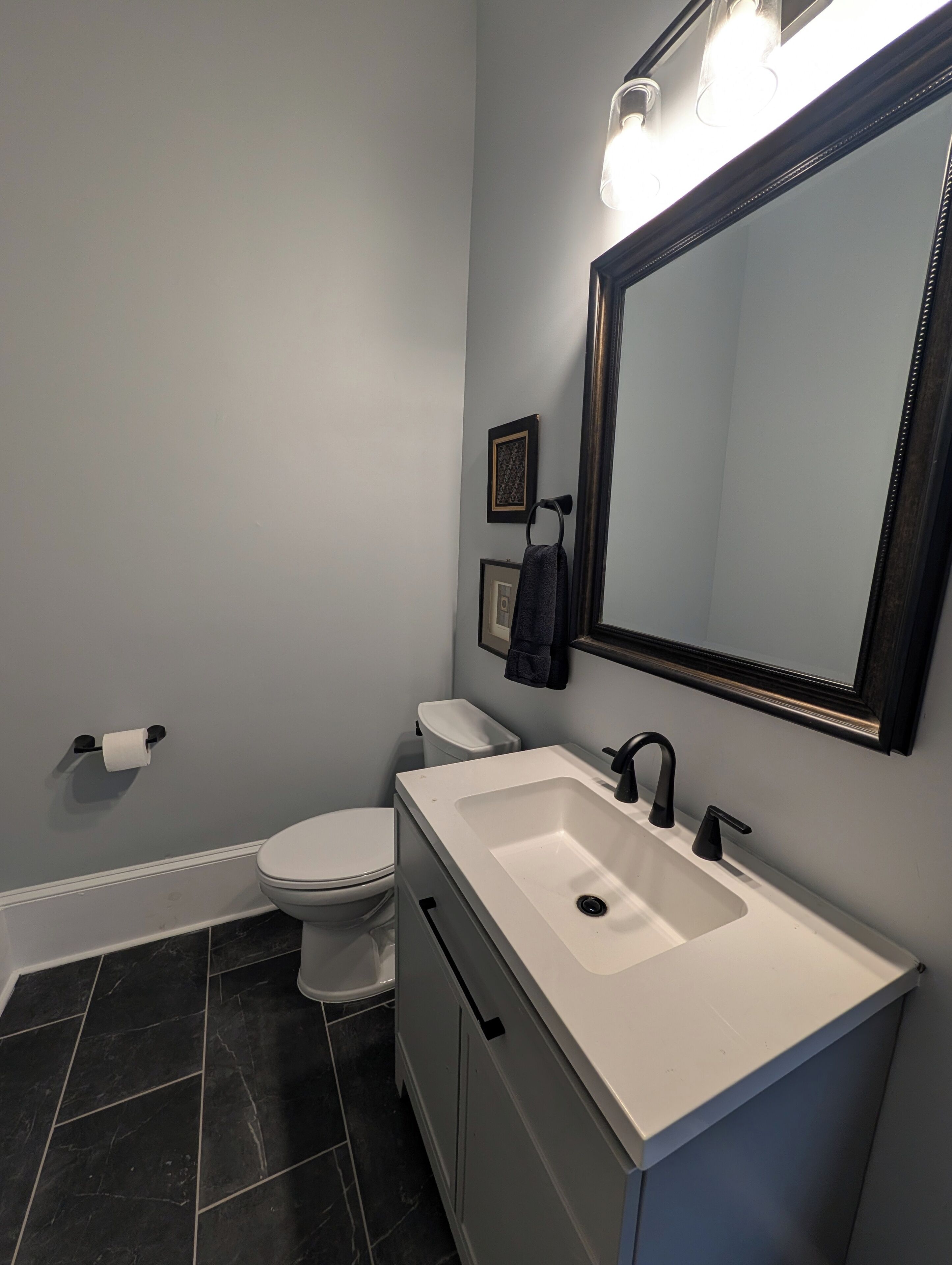 A bathroom with a white sink, black faucet, and a large mirror.