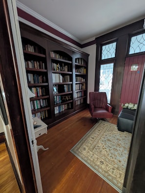 A library with bookshelves, a red chair, and a patterned rug.