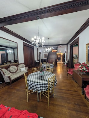 A spacious dining area with a high ceiling, chandeliers, and a staircase leading to an upper level. - Grande Magnolia of Benson (Benson)