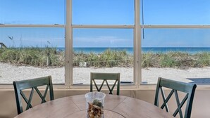 A table with chairs facing a large window overlooking a beach. - The Happy Turtle at Fisherman's Cove (Siesta Key)