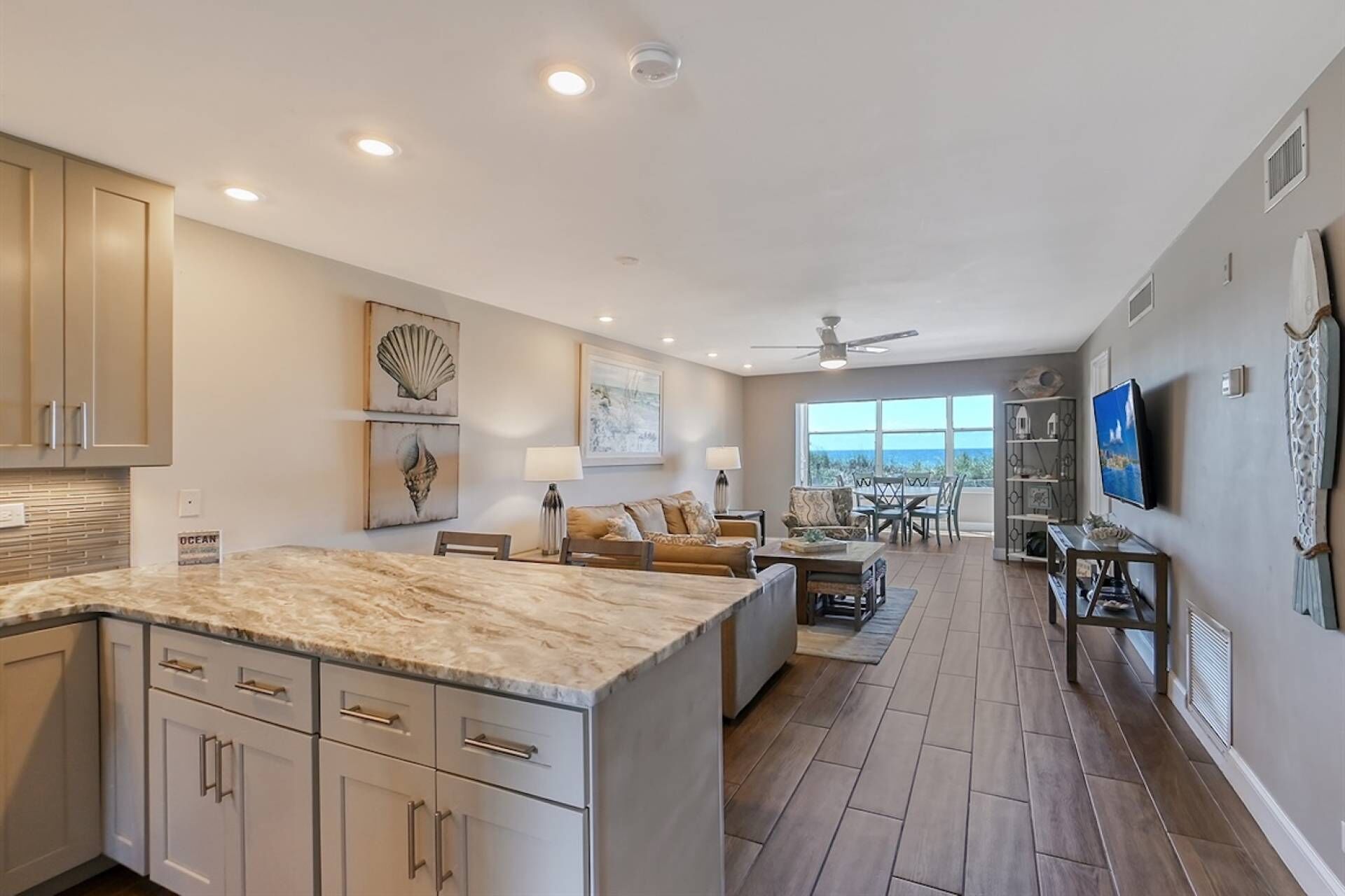 A spacious kitchen with a large island, a dining area with a view, and a living room with a TV and decorative items.