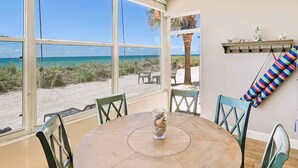 A beach view from a room with a round table, chairs, and a shelf with decorative items. - The Happy Turtle at Fisherman's Cove (Siesta Key)