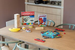 A dining table with various board games, including Monopoly and Guess Who?, and a yellow banana. - Hidden 18- St Ives Bay Suite Hot Tub (St Ives)