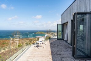 Ein Balkon mit Blick auf den Ozean, einem Tisch und Stühlen.