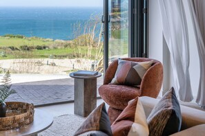 Ein modernes Zimmer mit einer Couch, einem kleinen Tisch und Meerblick.