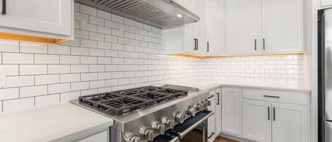A modern kitchen with white cabinetry, a stainless steel stove, and a built-in oven.