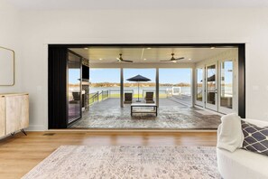 Ein geräumiges Zimmer mit einer großen Schiebeglasdoor, die auf eine Terrasse mit Seeblick und einem Boot führt.