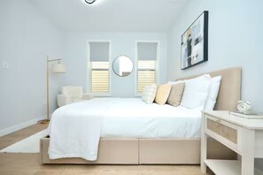 A bedroom with a bed, bedside table, lamp, and a framed picture on the wall. - Stylish - mins from airport - Modern - Clean (Boston)