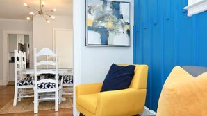 Ein Wohnzimmer mit einem gelben Sessel, einem grauen Sofa, einer blauen Akzentwand und einem modernen abstrakten Gemälde.