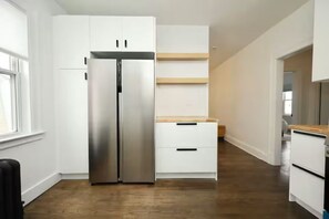 Cucina con mobili bianchi, frigorifero in acciaio inossidabile e piano di lavoro in legno.