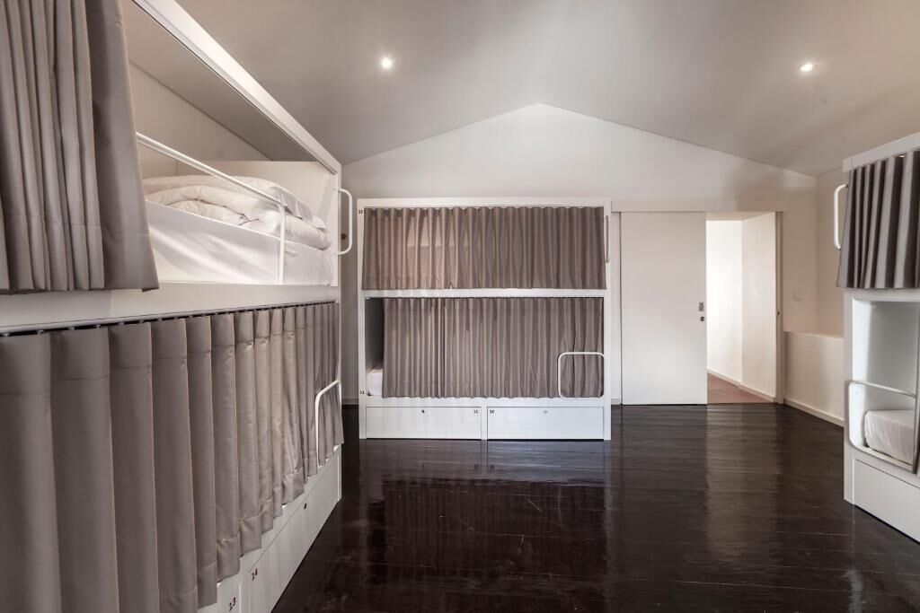 Une chambre moderne avec un lit superposé, une grande fenêtre avec des rideaux et un plancher en bois foncé.