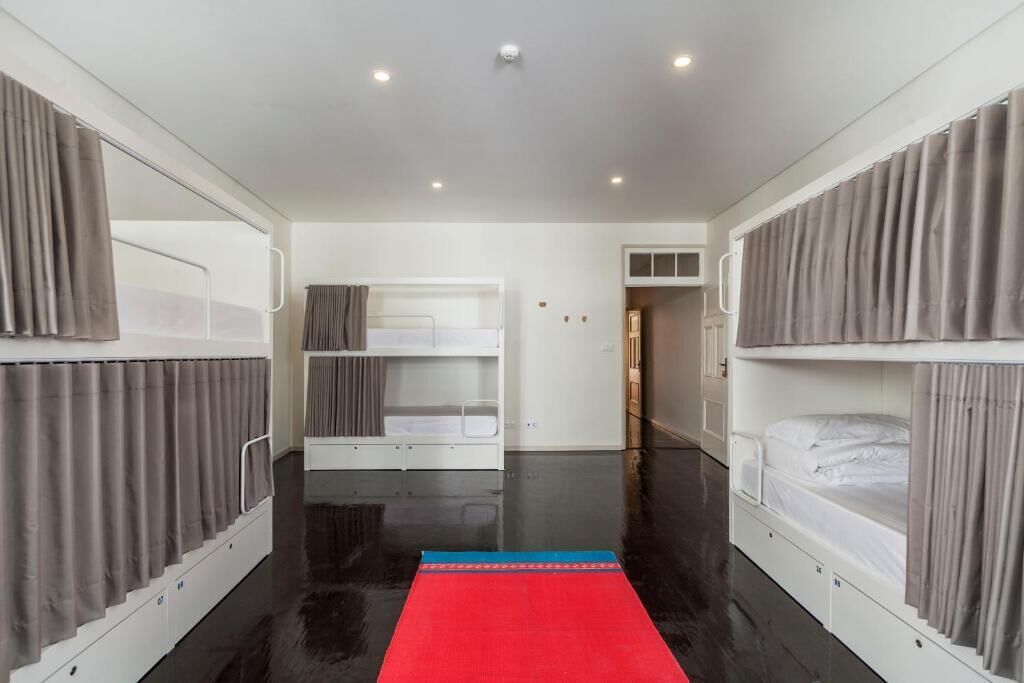 Una habitación con literas, un aparador blanco y una alfombra roja.