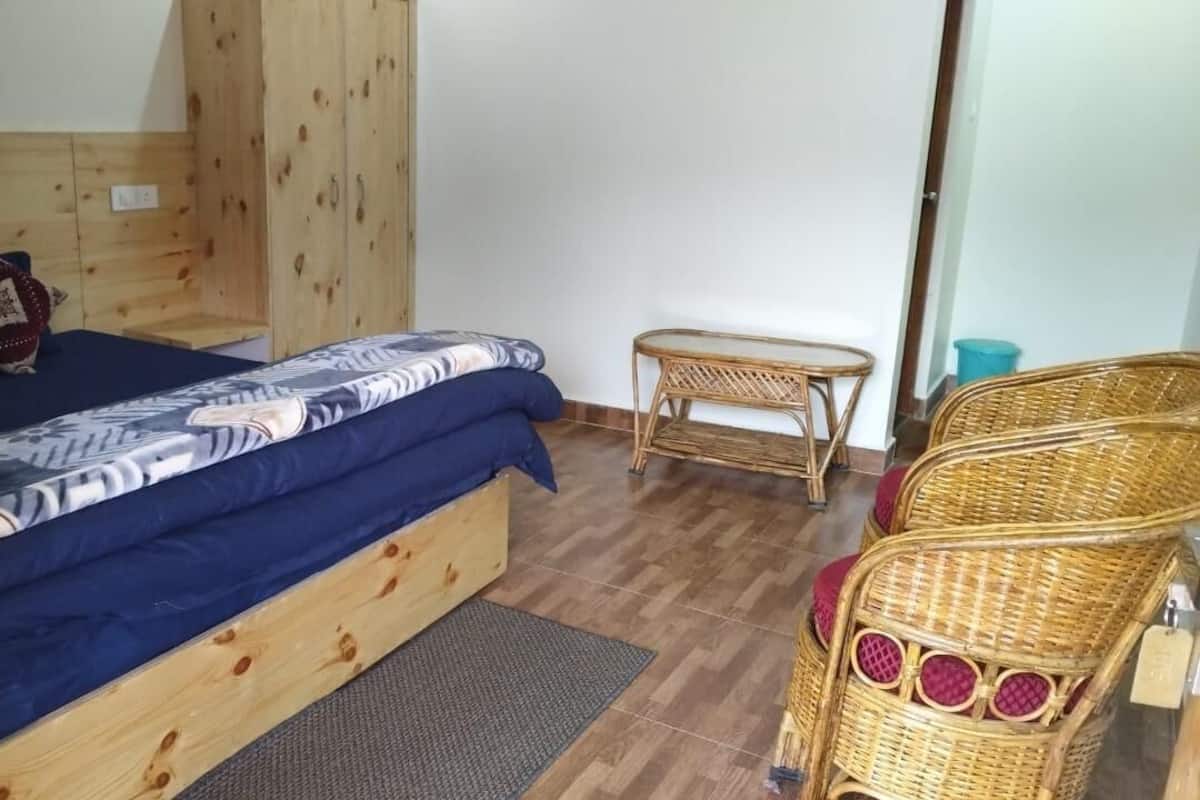 A room with a wooden bed, a bench, and wicker chairs.