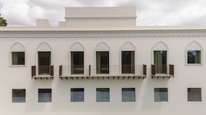 Un bâtiment doté d’une façade symétrique, de nombreuses fenêtres en arc de cercle et d’un balcon agrémenté d’une balustrade.