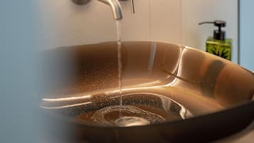 Une salle de bain moderne avec un lavabo en verre, un robinet et un distributeur de savon.