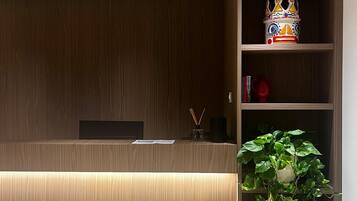 Un comptoir d’accueil avec un revêtement en bois, une plante en pot et une étagère ornée d’objets décoratifs.