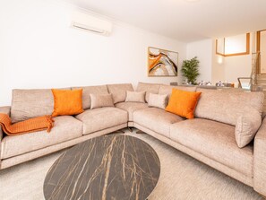 A modern living room with a sectional sofa, a round coffee table, and a painting on the wall. - Escape Exclusivo em Tavira (Tavira)