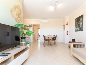 Ein modernes Wohnzimmer mit Flachbildfernseher, einem Essbereich mit Tisch und Stühlen sowie einem Sofa.