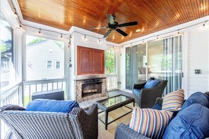 A covered porch with wicker furniture, a glass-top table, a fireplace, and a ceiling fan. - New Rental - Reynolds Lake Ocone 3 BR 2.5 Bath Cottage (Greensboro)