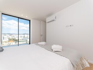 Ein modernes Hotelzimmer mit einem großen Bett, Blick auf die Stadt und einer Klimaanlage.