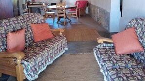 A living room with patterned sofas, a dining table, and chairs. - Off-grid Cottage Mountain Views Horses & Sunset (Bergrivier)