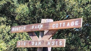 A wooden directional sign with the text 'Rustic Farm Cottage' and 'Die Dam Huis'. - Off-grid Cottage Mountain Views Horses & Sunset (Bergrivier)