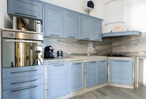 A modern kitchen with built-in appliances, light blue cabinetry, and a marble backsplash. - Villa 'Sea Sunset' with Private Terrace, Wi-Fi and Air Conditioning (San Pietro In Bevagna)