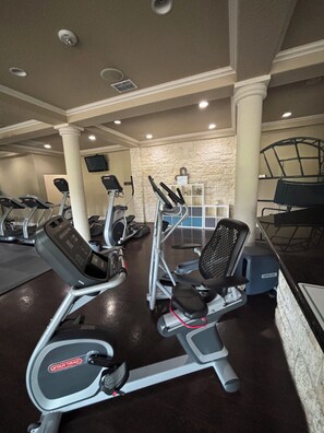 A gym with treadmills, elliptical machines, and a weight bench.