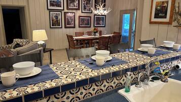 A kitchen with a long countertop, a sink, and a dining area with chairs and a table.