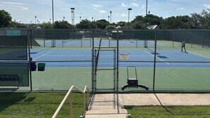 Tässä on tenniskenttä, jossa on aita, penkki ja kyltti, josta ilmenee, että alue on tarkoitettu vain jäsenille.
