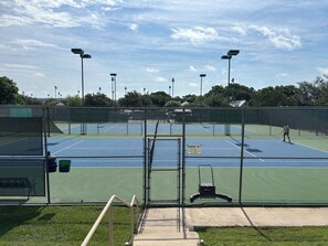 A tennis court with a fence, a bench, and a sign indicating it's a members-only area.