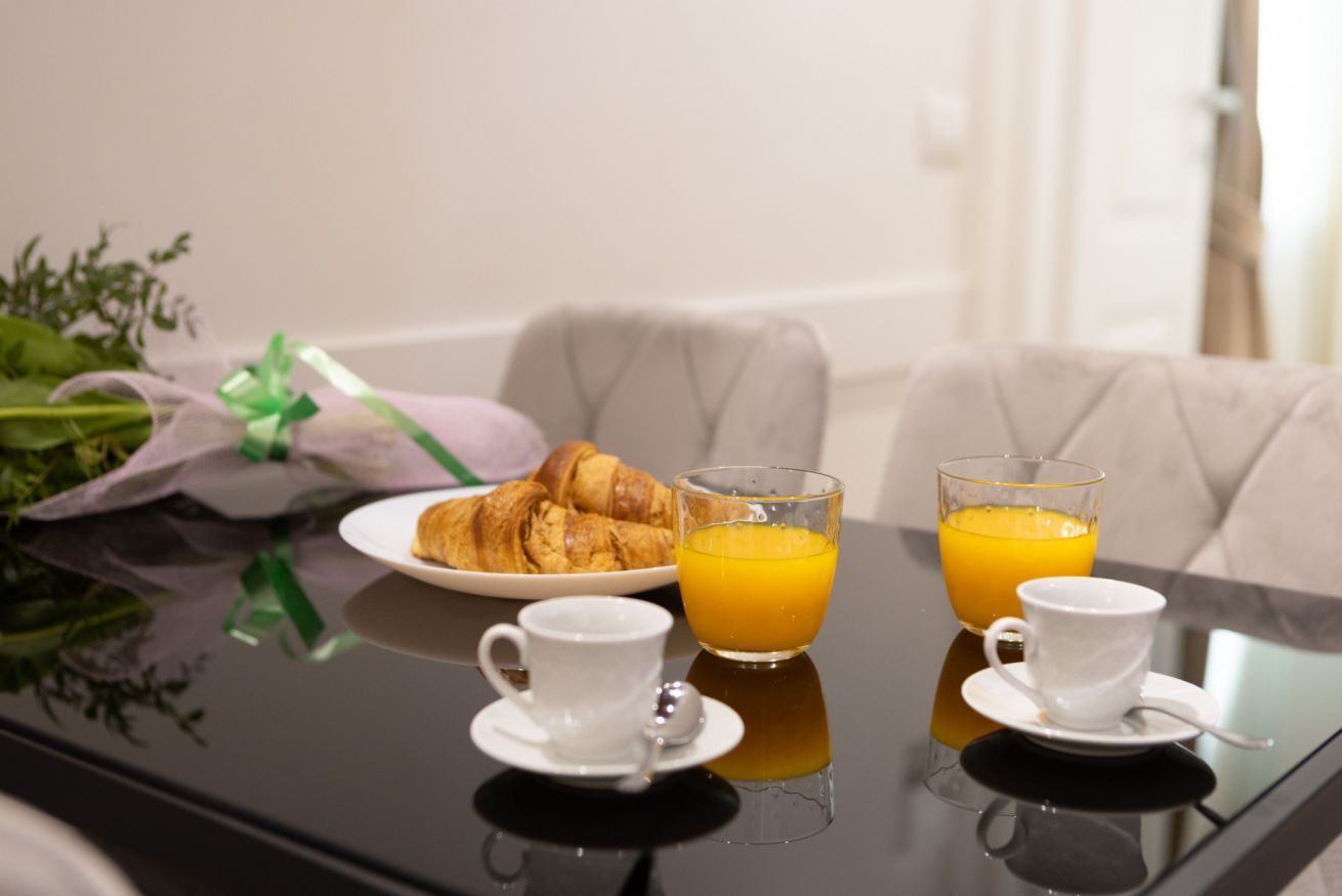 Ein Frühstücksaufenthalt mit Croissants, Orangensaft und Kaffee auf einem spiegelnden Tisch.
