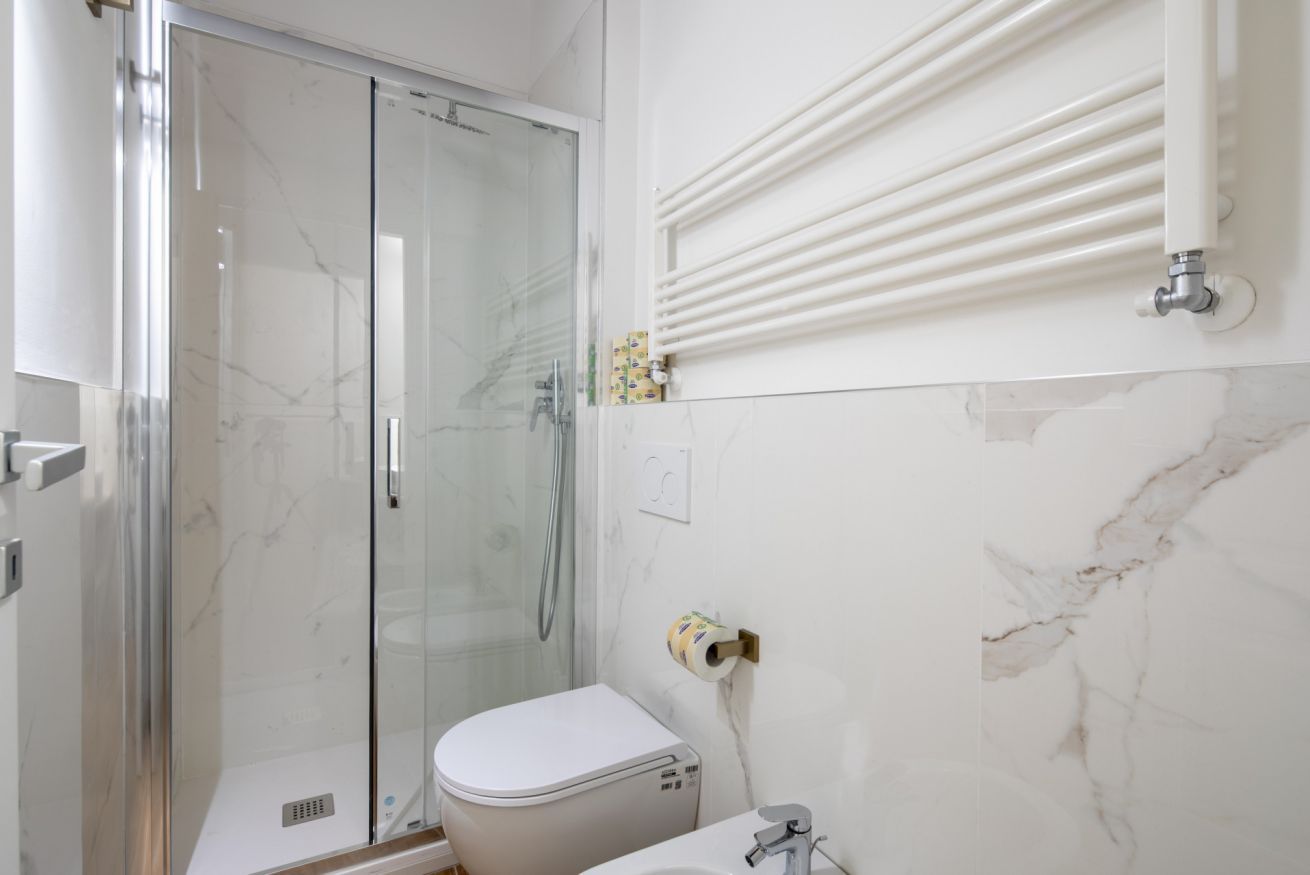 Ein Badezimmer mit Duschkabine, Toilette, Waschbecken und Handtuchhalter.