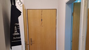 A hallway with a wooden door, a coat rack with a black garment, and a blue door on the right.