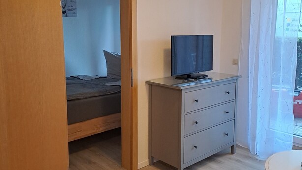 A room with a bed, a desk, a television, and a small table.