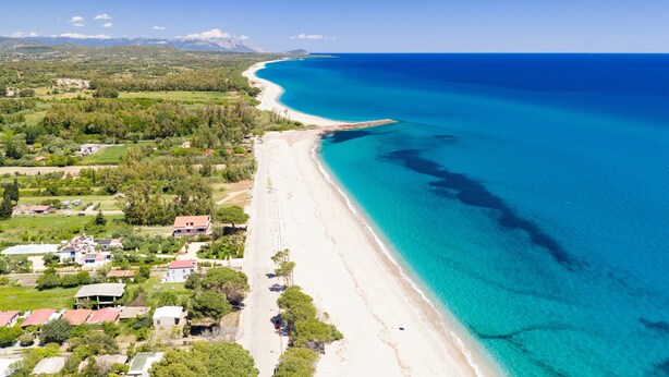 Oversigtsbillede af et kystområde med strand, huse og grønt.