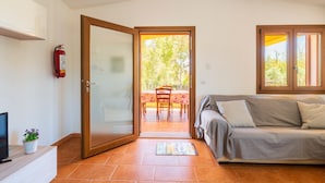 A room with a sliding glass door leading to an outdoor patio, a sofa, a television, and a fire extinguisher. - Apartment 'Casa Delle Mimose Con Terrazza' with Private Terrace, Wi-Fi and Air Conditioning (Cardedu)