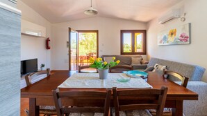 A dining area with a wooden table, chairs, a vase of flowers, and a television on the wall. - Apartment 'Casa Delle Mimose Con Terrazza' with Private Terrace, Wi-Fi and Air Conditioning (Cardedu)