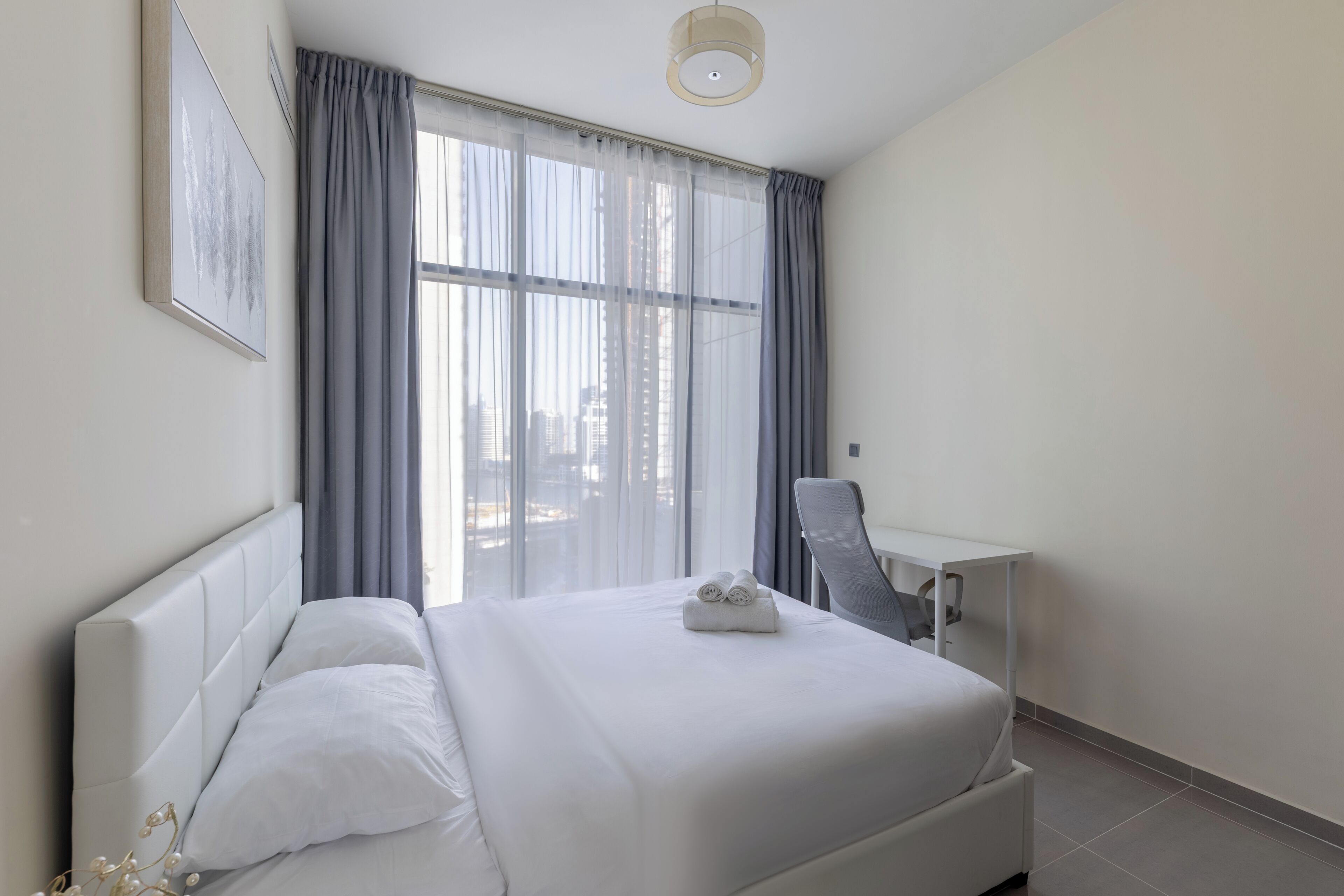 A hotel room with a bed, a desk, and a chair.